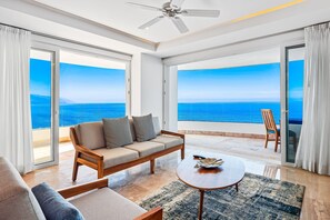 Ein geräumiger Balkon mit Blick auf den Ozean, eine Couch, ein Couchtisch und ein Stuhl.