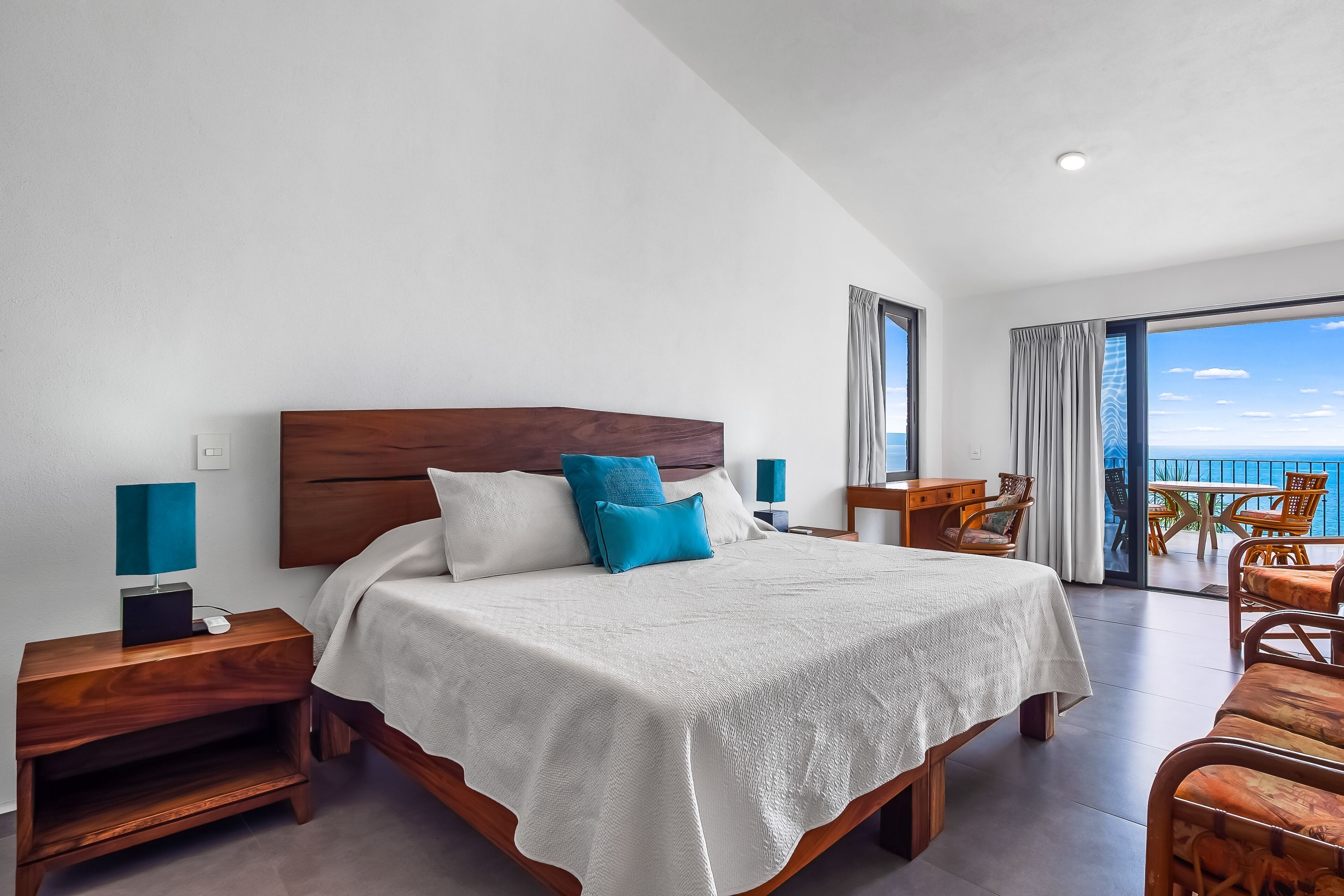 Une chambre spacieuse avec un grand lit, un bureau et une vue sur l’océan.