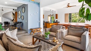 A modern living room with a sofa set, a coffee table with decorative items, and a staircase leading to an upper level. - Ocean-view Conchas Chinas 3BR near beaches, dining, nightlife (Puerto Vallarta)