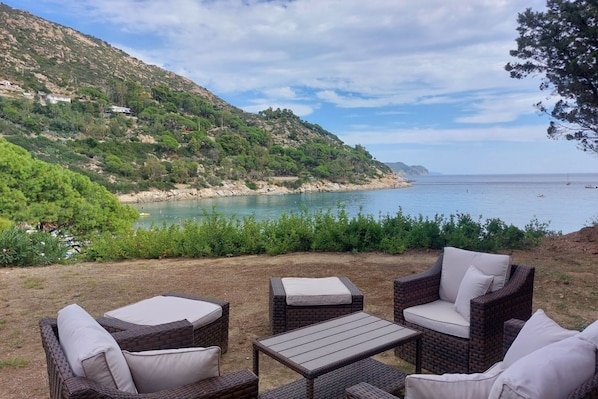 Un espace extérieur aménagé en bord de mer, avec des meubles en osier et une vue sur l’océan.