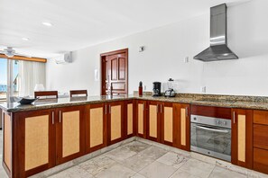 Eine moderne Küche mit Holzausstattung, einem eingebauten Backofen und einer Edelstahl-Dunstabzugshaube.