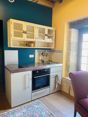 Une cuisine compacte dotée d’un four encastré, d’un évier et de meubles hauts.