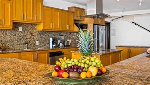 A kitchen with granite countertops, wooden cabinets, stainless steel appliances, and a fruit bowl on the counter. - Elegant multi-level penthouse with rooftop Jacuzzi, bay views, pool & game room (Puerto Vallarta)
