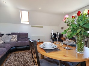 A dining area with a round table set for two, a sofa, and a window above the table.