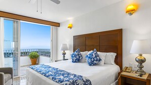 A hotel room with a large bed, two bedside lamps, a wooden headboard, and a balcony with a view. - Elegant bayview suite with terrace access, full kitchen, pool, hot tub & gym (Puerto Vallarta)