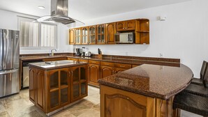 A kitchen with wooden cabinets, stainless steel appliances, and a granite countertop. - Elegant bayview suite with terrace access, full kitchen, pool, hot tub & gym (Puerto Vallarta)