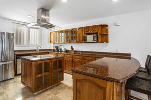Eine Küche mit Holzschränken, Edelstahlgeräten und einer Arbeitsplatte aus Granit.