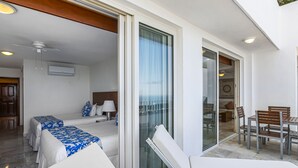 A hotel room with a balcony, a bed, a chair, a table, and a ceiling fan. - Elegant bayview suite with terrace access, full kitchen, pool, hot tub & gym (Puerto Vallarta)