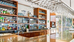 Un bar avec des étagères remplies de bouteilles d’alcool, un comptoir en granit poli et des luminaires suspendus.