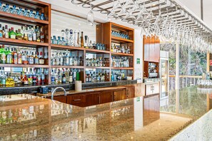 A bar with shelves of liquor bottles, a polished granite countertop, and hanging light fixtures. - Elegant hillside villa with panoramic views, pool, hot tub & luxe interiors (Puerto Vallarta)