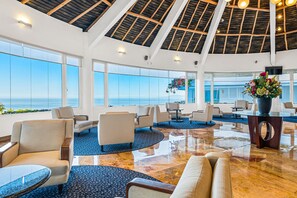 A spacious lobby with a high ceiling, large windows offering a view of the sea, and a variety of seating arrangements. - Elegant hillside villa with panoramic views, pool, hot tub & luxe interiors (Puerto Vallarta)