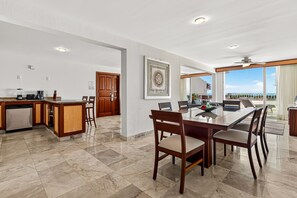A spacious kitchen with a dining area, a large window with a view, and a ceiling fan. - Coastal retreat condo with resort-style pool, hot tub & oceanfront terrace (Puerto Vallarta)