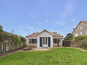 Ein zweistöckiges Haus mit Ziegeldach, einer Veranda und einem kleinen Garten.