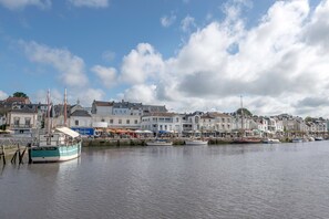 Ein Hafen mit vertäuten Booten, Gebäuden an der Uferlinie und einem klaren Himmel.