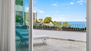 Een balkon met uitzicht op zee, een witte balustrade en een witte tafel.