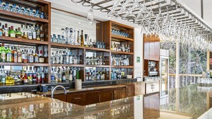 A bar area with shelves of liquor bottles, a polished granite countertop, and hanging light fixtures. - Stunning oceanview suite with cliffside infinity pool, terrace & gourmet kitchen (Puerto Vallarta)
