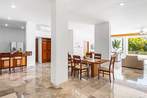 Eine geräumige Küche mit Essbereich, Holzschränken und einem großen Fenster mit Blick auf einen Garten.