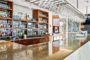 A bar area with shelves of liquor bottles, a polished granite countertop, and a hanging light fixture. - Upscale bayview villa with hot tub, private terrace, pool & stylish interiors (Puerto Vallarta)