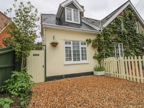 A house with a beige exterior, a white window, and a gravel driveway.