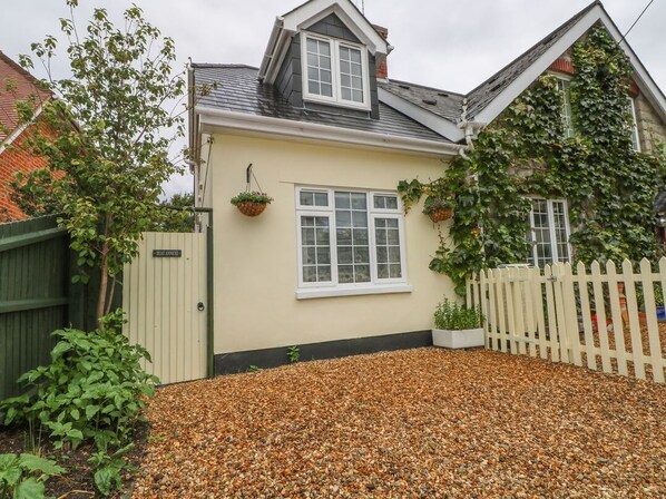 A house with a beige exterior, a white window, and a gravel driveway.