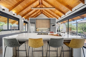 Una cocina moderna con una isla grande, taburetes de bar y vistas al exterior.