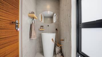 Ein Badezimmer mit Holztür, Waschbecken, Spiegel und Handtuchhalter.