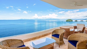 A balcony with wicker furniture and a glass table overlooking the sea. - Blue Horizon 401 | 1BR/2BA | PV Ocean View, Pool (Puerto Vallarta)