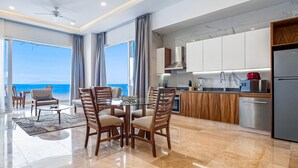 A modern kitchen with a view of the sea, a dining area with a round table, and a balcony with chairs. - Blue Horizon 401 | 1BR/2BA | PV Ocean View, Pool (Puerto Vallarta)