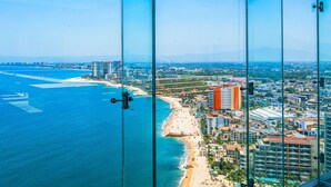 A coastal cityscape with a beach, high-rise buildings, and clear skies. - Summer Deal 1BR Puerto Vallarta condo w/ pool, gym (Puerto Vallarta)