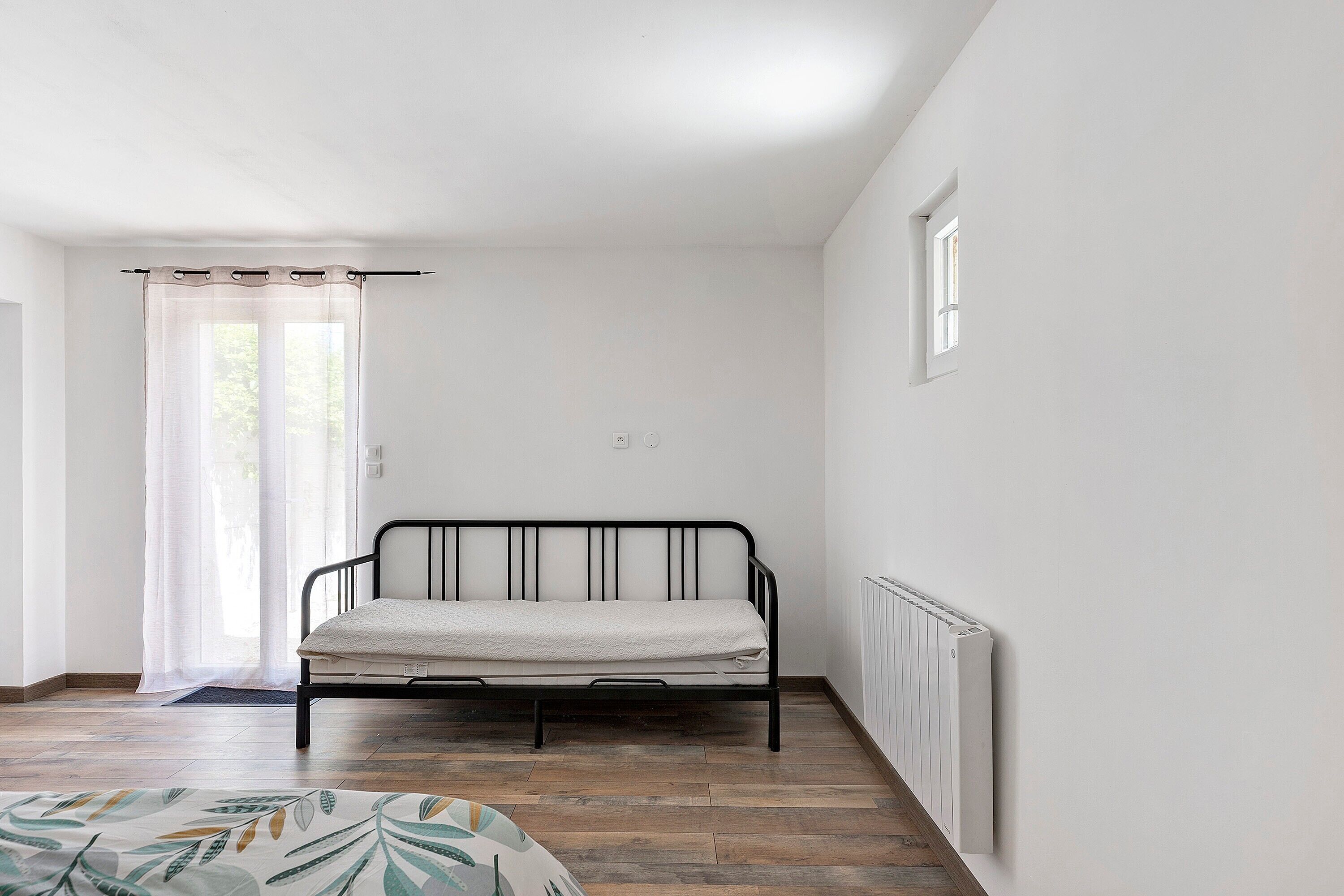 A room with a bed, a radiator, a window, and a door.
