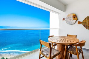 Ein Balkon mit Blick auf das Meer, ein runder Holztisch und zwei Holzstühle.