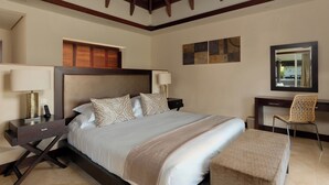 A hotel room with a large bed, bedside tables, a desk, and a chair. - Peaceful 4-Bedroom Villa / Infinity Pool & Garden View (Bel Ombre)
