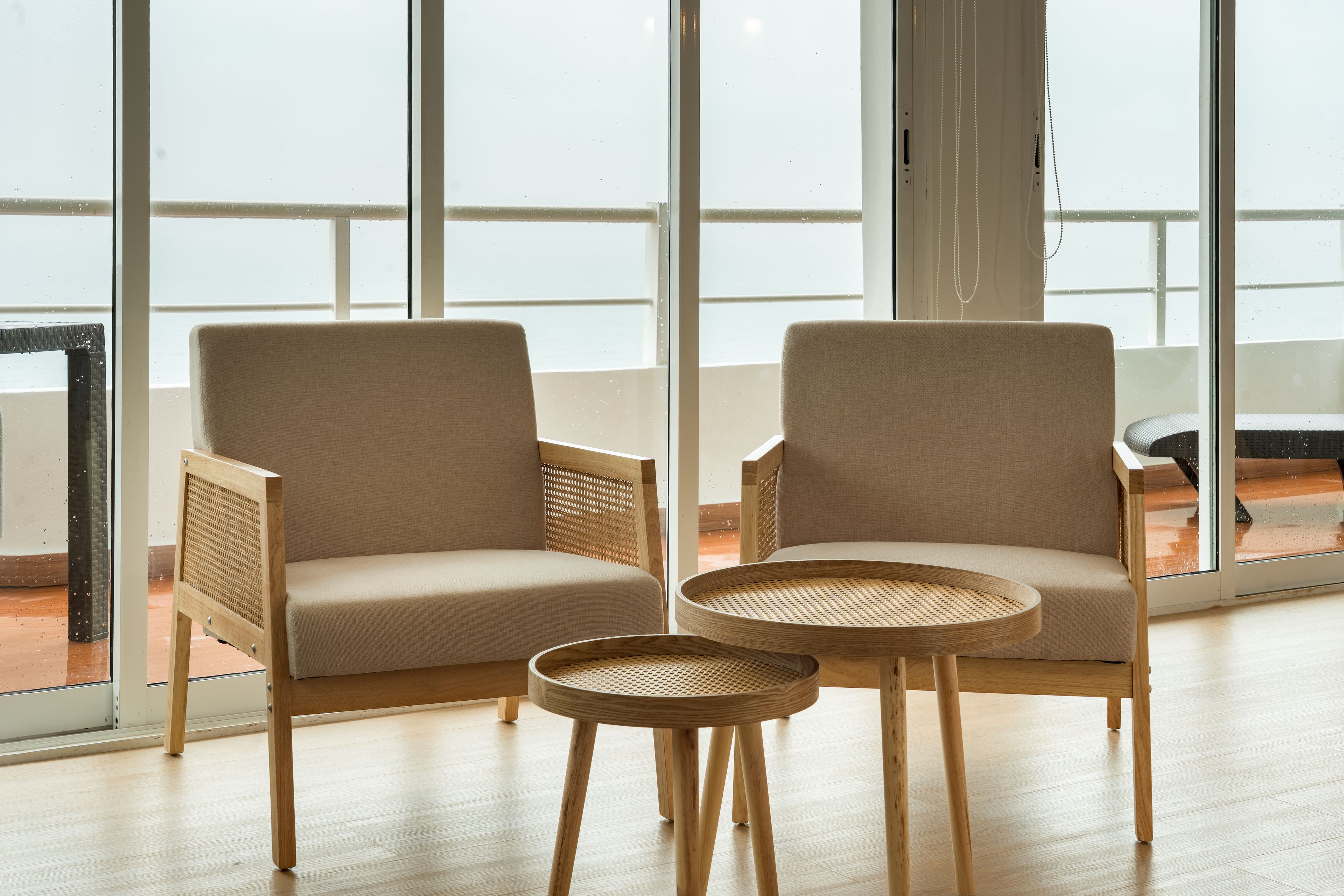 Two armchairs and a round table in a room with large windows.