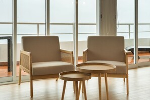 Deux fauteuils et une table ronde dans une pièce dotée de grandes fenêtres.