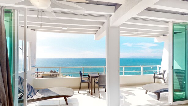 Ein Balkon mit Meerblick, ausgestattet mit Stühlen und einem Tisch.