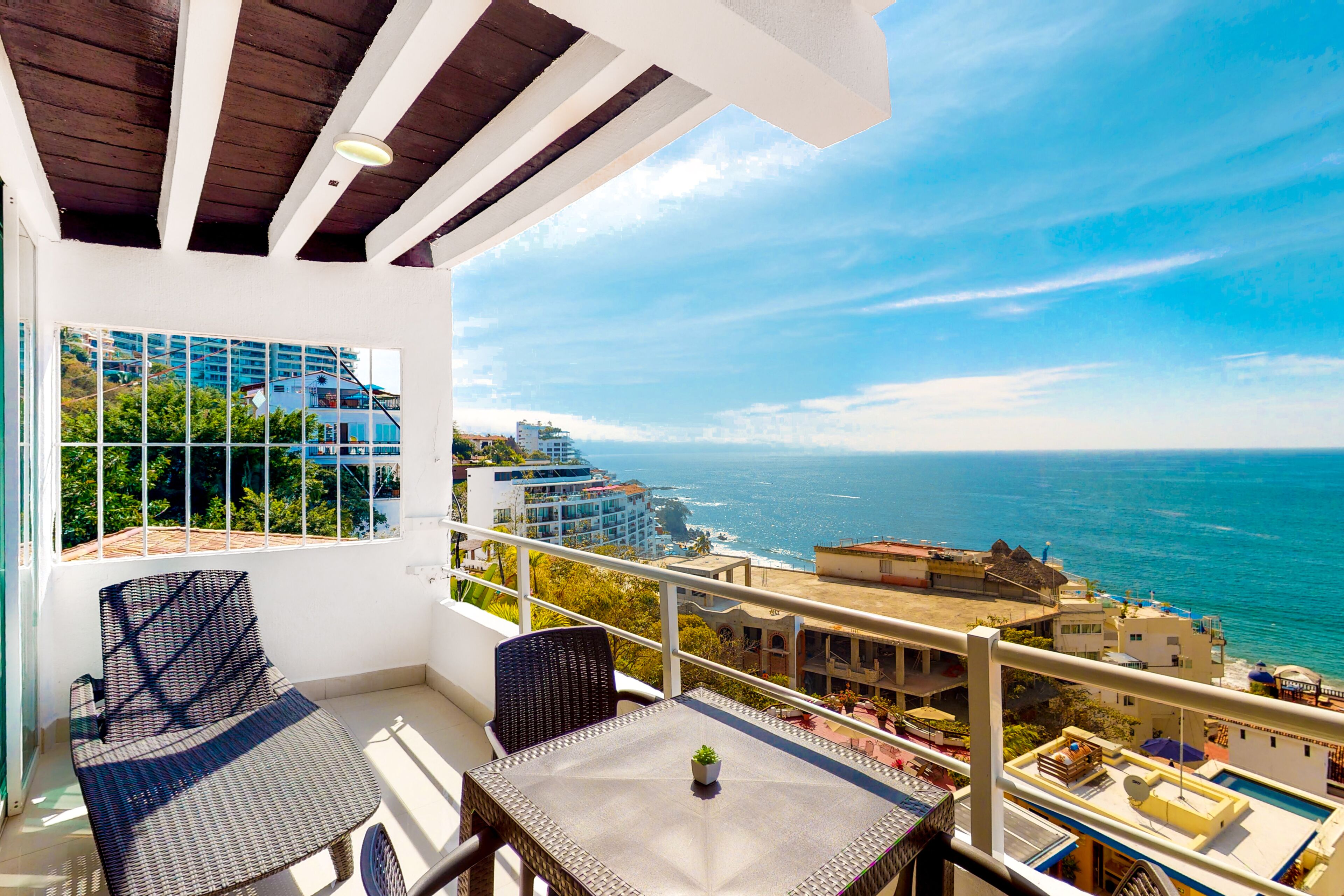 Un balcon avec vue sur l’océan, une table et deux chaises.