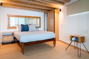 Une chambre à coucher comprenant un lit, une table de chevet, une commode, un miroir, une armoire et un haut-parleur.