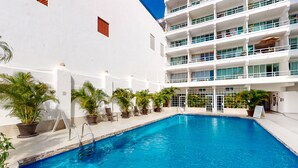 Ein Swimmingpool neben einem weißen Gebäude mit Balkonen.