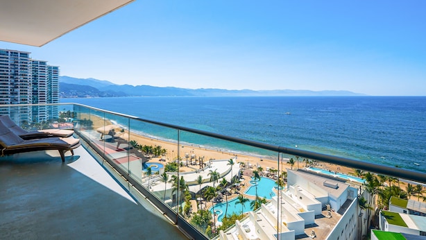Ein Balkon mit Liegestühlen mit Blick auf Strand und Poolbereich.
