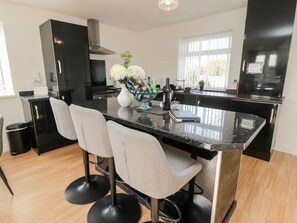 A modern kitchen with a central island, bar stools, and a decorative vase.