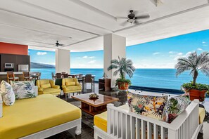 A spacious room with a large bed, yellow armchairs, a wooden coffee table, and a view of the ocean. - Blue Horizon 1102 | 2BR/2BA Puerto Vallarta | Ocean View, Pool, Gym (Puerto Vallarta)