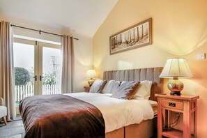 Een hotelkamer met een bed, twee bedlampen, een schilderij aan de muur en uitzicht door een schuifdeur.
