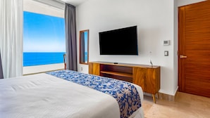 Une chambre d’hôtel avec un grand lit, une télévision, une commode en bois et une vue sur l’océan.