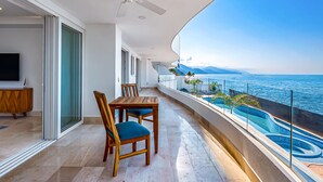 Un balcon avec une table et des chaises, un ventilateur de plafond et une vue sur la mer.