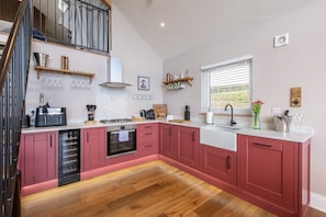 A modern kitchen with pink cabinets, a built-in oven, and a stainless steel range hood. - Hare's Hill, Thornton-Le-Dale (Pickering)
