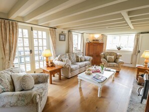 Una sala de estar acogedora con piso de madera, una mesa de centro blanca y dos sofás.