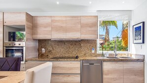Een moderne keuken met houten kastjes, een granieten aanrecht en een ingebouwde vaatwasser.