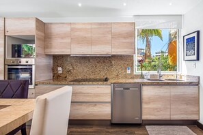 A modern kitchen with wooden cabinets, a granite countertop, and a built-in dishwasher. - Scala 303 | 1BR Puerto Vallarta | Near Beach & Downtown (Puerto Vallarta)