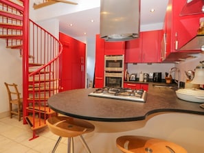 Una cocina moderna con armarios rojos, una isla central, una estufa a gas y un horno de acero inoxidable.