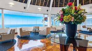 A spacious lobby with a large glass table, comfortable seating, and a view of the ocean. - Well-located hillside suite with rooftop pool, fitness center & family features (Puerto Vallarta)